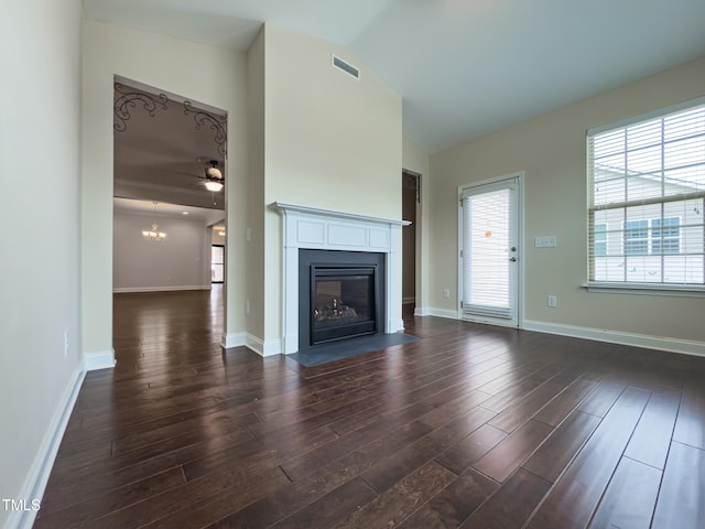 unfurnished living room with dark hardwood / wood-style floors, ceiling fan with notable chandelier, and high vaulted ceiling