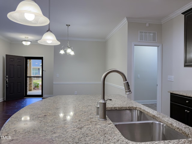 kitchen with light stone counters, hanging light fixtures, and crown molding