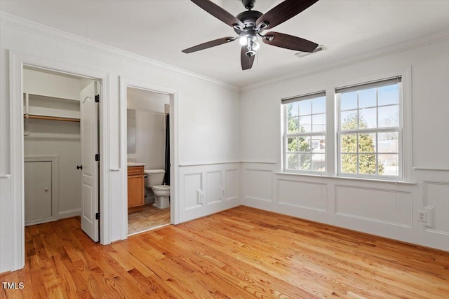 unfurnished bedroom with light wood-style flooring, visible vents, ornamental molding, a closet, and a walk in closet