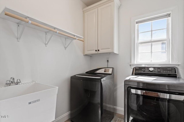 washroom featuring baseboards, a sink, cabinet space, and washer and dryer