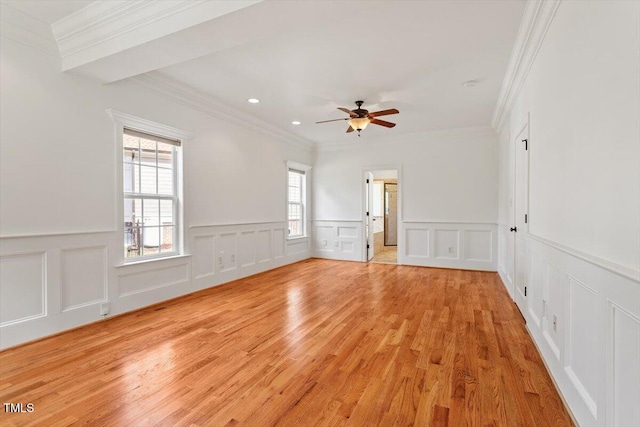 spare room with ceiling fan, a decorative wall, light wood-type flooring, and crown molding