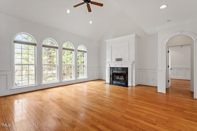 unfurnished living room with a fireplace with flush hearth, a decorative wall, light wood finished floors, and ceiling fan