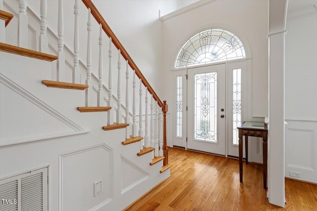 foyer with a wealth of natural light, light wood-style flooring, and a high ceiling