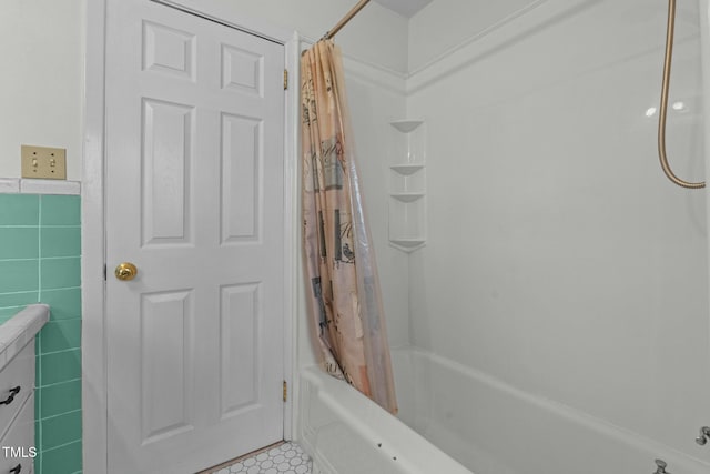 bathroom with tile walls and shower / bath combo with shower curtain