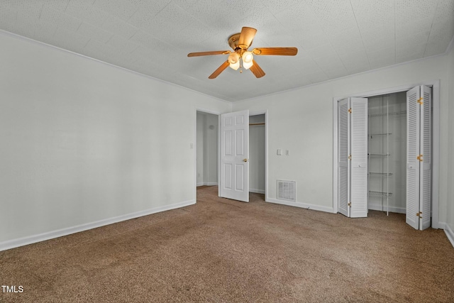 unfurnished bedroom with multiple closets, ceiling fan, carpet floors, and a textured ceiling