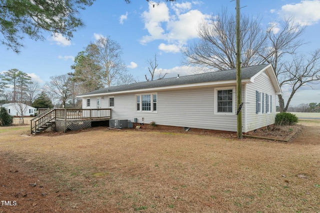 rear view of property featuring central AC unit, a yard, and a deck