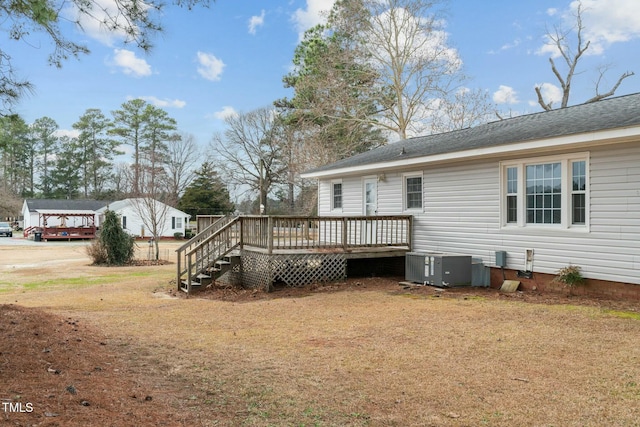 rear view of house featuring cooling unit, a lawn, and a deck