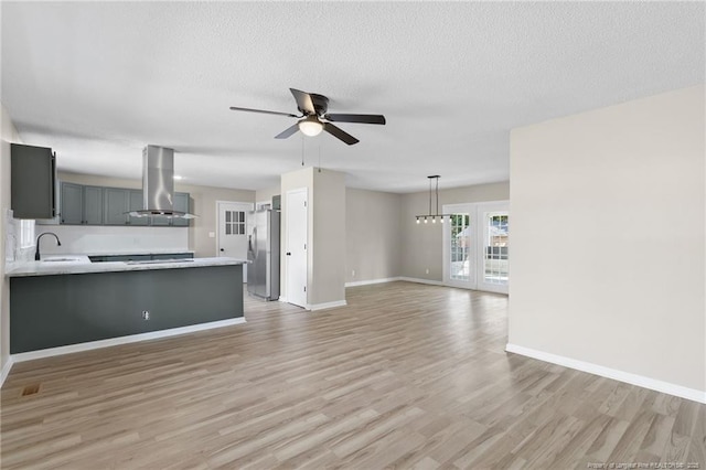 unfurnished living room with sink, a textured ceiling, light hardwood / wood-style flooring, and ceiling fan