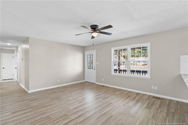 empty room with ceiling fan, a textured ceiling, and light hardwood / wood-style flooring