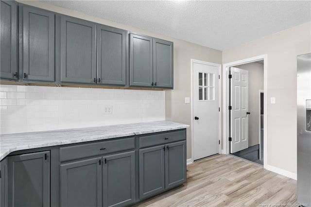 kitchen with tasteful backsplash, gray cabinets, a textured ceiling, and light wood-type flooring