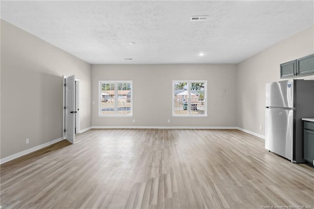 unfurnished living room with light hardwood / wood-style flooring and a textured ceiling