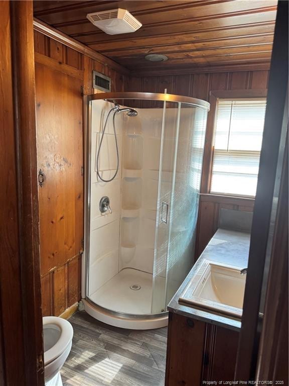 bathroom featuring hardwood / wood-style floors, wooden walls, vanity, wood ceiling, and a shower with door