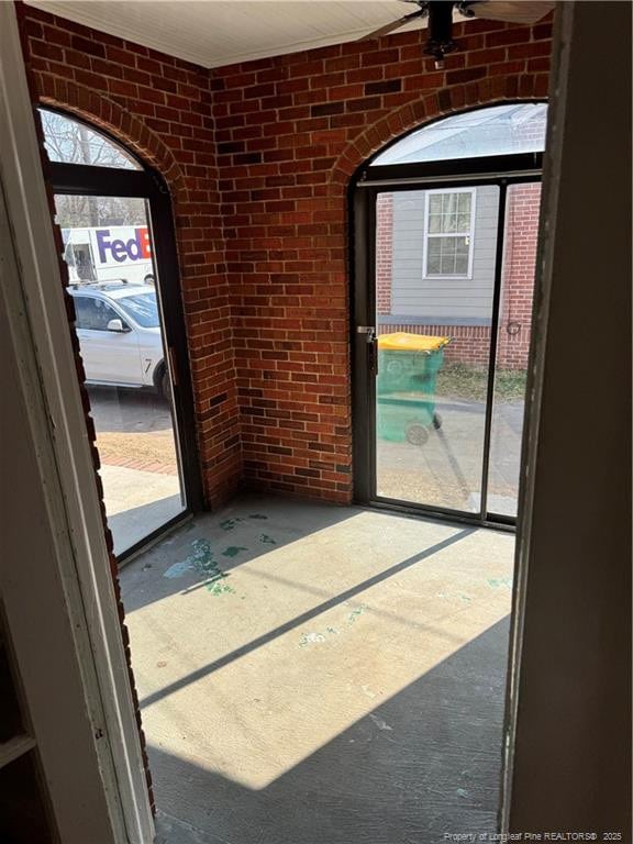 entryway with brick wall and concrete flooring