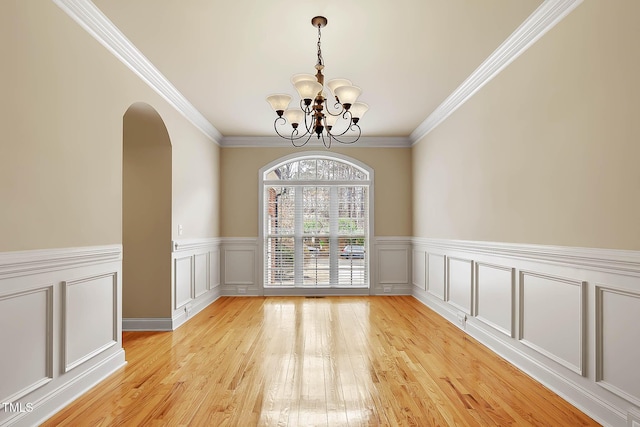 unfurnished room featuring an inviting chandelier, crown molding, and light hardwood / wood-style floors