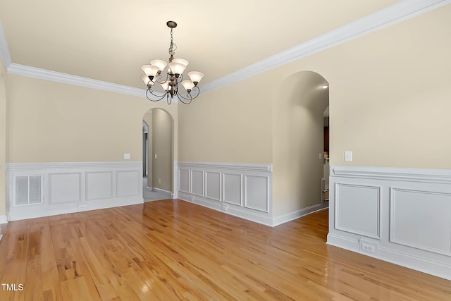 unfurnished dining area with ornamental molding, a chandelier, and light wood-type flooring