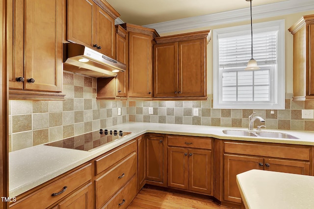 kitchen with sink, crown molding, decorative light fixtures, black electric cooktop, and backsplash