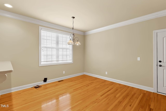 empty room featuring a notable chandelier, hardwood / wood-style flooring, and ornamental molding