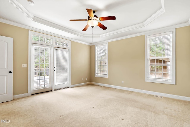 carpeted empty room with a raised ceiling, ornamental molding, and ceiling fan