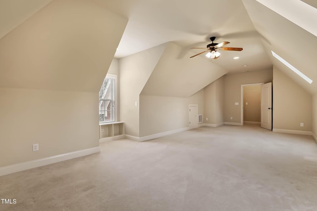 bonus room with ceiling fan, light colored carpet, and vaulted ceiling with skylight