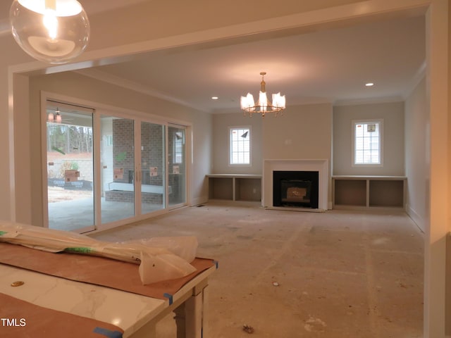 unfurnished living room featuring crown molding, a fireplace, an inviting chandelier, and a healthy amount of sunlight