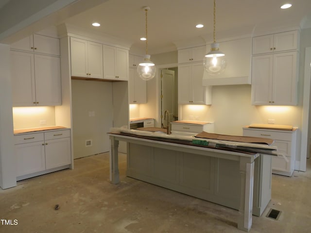 kitchen featuring white cabinetry, hanging light fixtures, an island with sink, and a kitchen bar