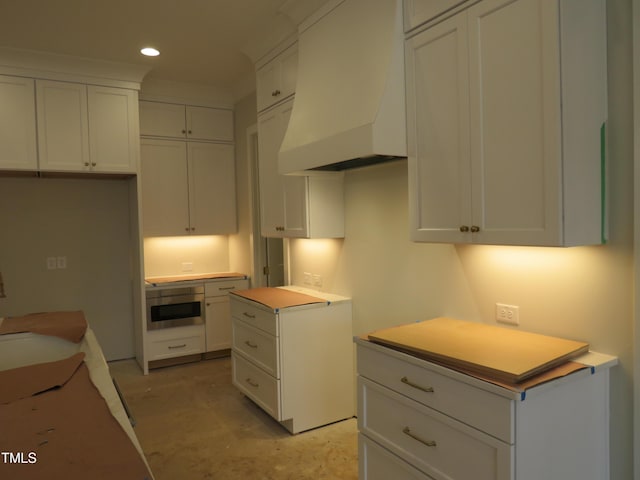 kitchen with white cabinetry and custom range hood