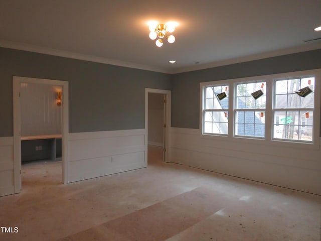 spare room featuring a wainscoted wall, crown molding, and visible vents