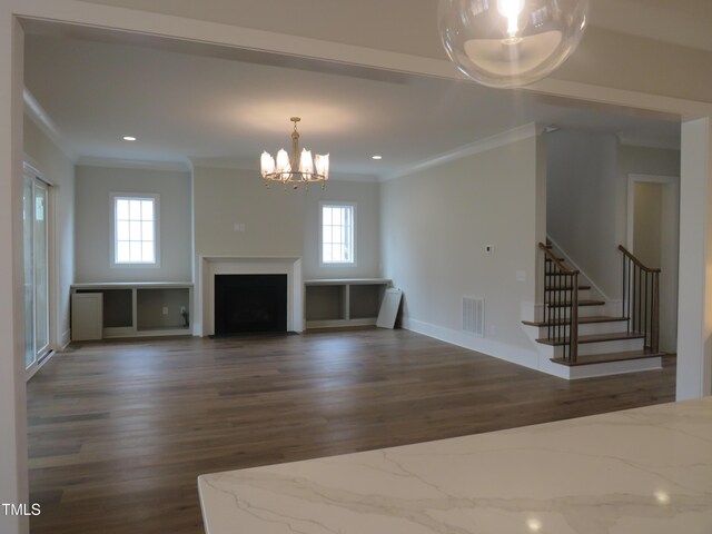 unfurnished living room featuring a notable chandelier, wood finished floors, visible vents, and plenty of natural light