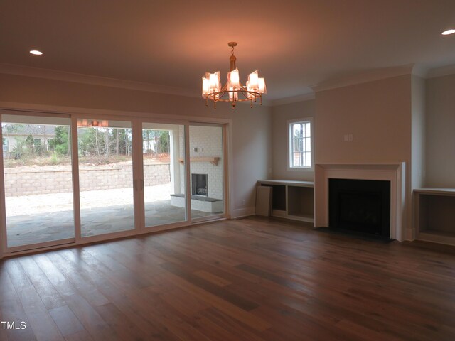 unfurnished living room featuring crown molding, a chandelier, recessed lighting, a fireplace, and dark wood-style flooring