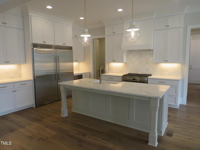 kitchen with dark wood finished floors, pendant lighting, appliances with stainless steel finishes, white cabinets, and a kitchen island with sink
