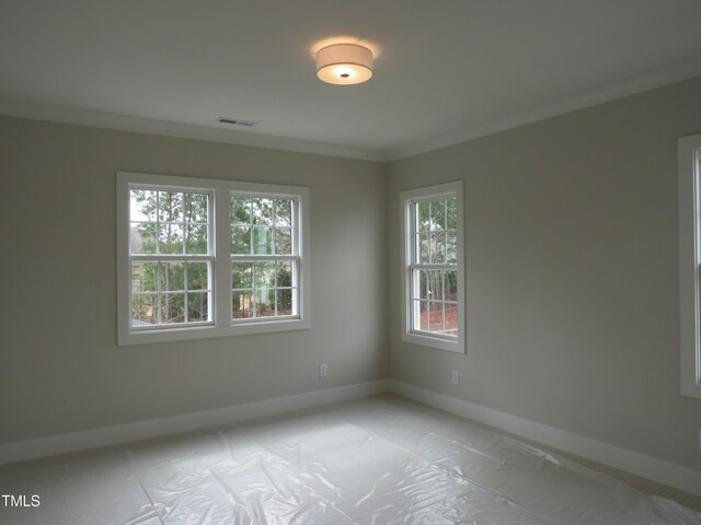 unfurnished room with visible vents, baseboards, and ornamental molding