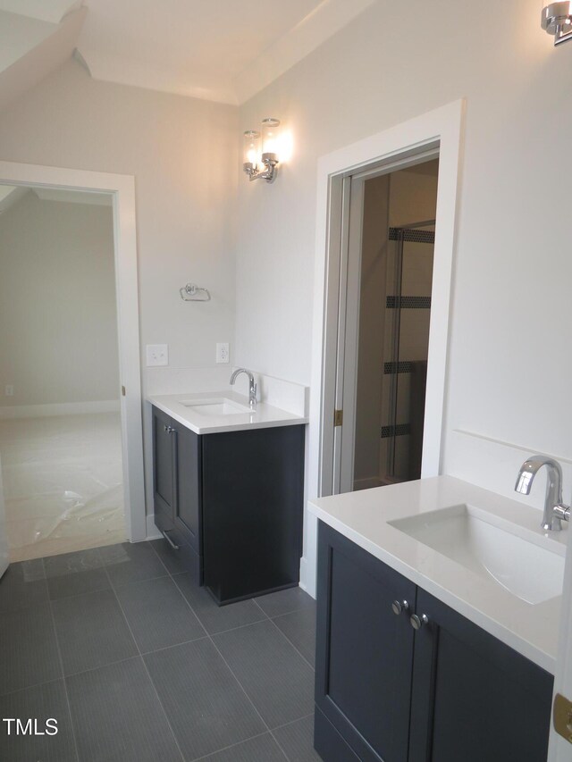 full bathroom with a sink, two vanities, a stall shower, and tile patterned floors