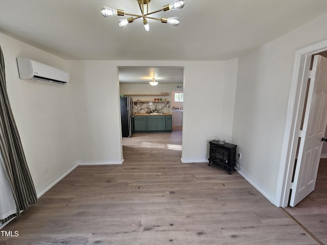 hallway with sink, a wall mounted air conditioner, light wood-type flooring, a notable chandelier, and washer and clothes dryer