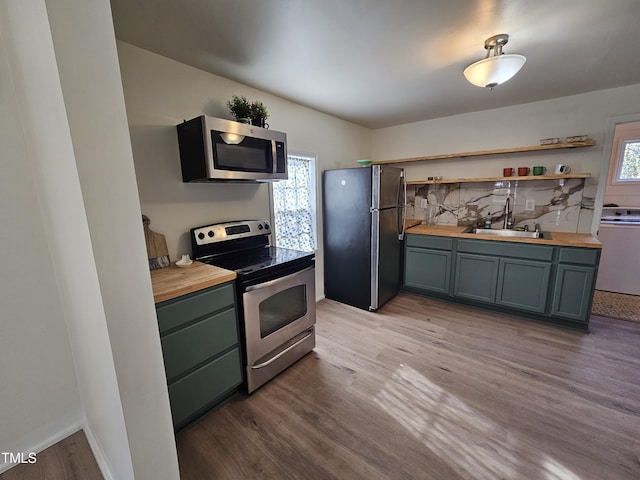 kitchen with butcher block counters, sink, light hardwood / wood-style flooring, appliances with stainless steel finishes, and a wealth of natural light