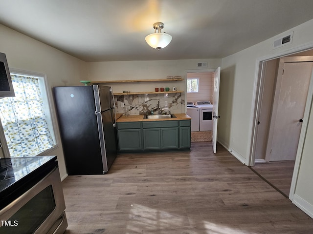 kitchen featuring sink, a wealth of natural light, stainless steel fridge, and washing machine and dryer