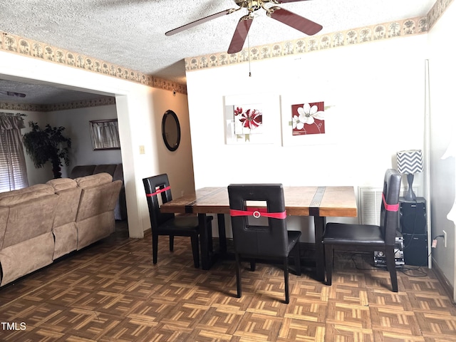 dining area featuring ceiling fan, dark parquet flooring, and a textured ceiling