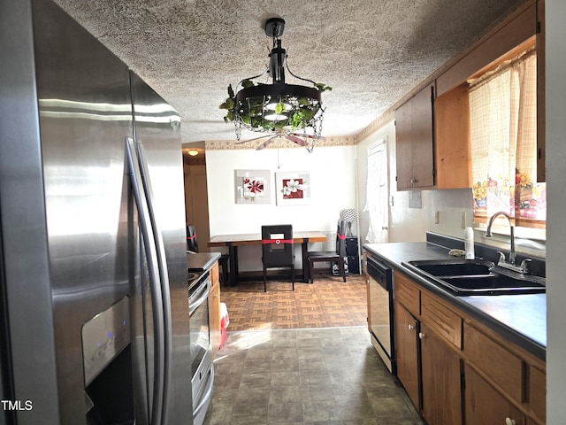 kitchen featuring stainless steel appliances, hanging light fixtures, sink, and a textured ceiling