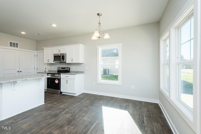 kitchen with a breakfast bar, white cabinetry, light stone counters, decorative light fixtures, and appliances with stainless steel finishes