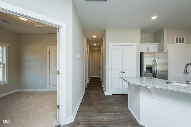 kitchen with sink, white cabinets, a kitchen breakfast bar, light stone counters, and stainless steel refrigerator with ice dispenser