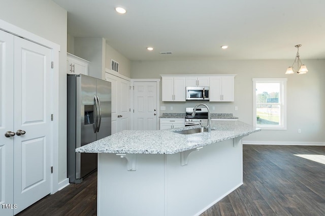 kitchen featuring sink, decorative light fixtures, appliances with stainless steel finishes, a kitchen island with sink, and white cabinets