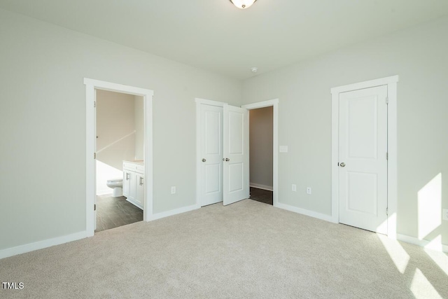 unfurnished bedroom with connected bathroom and light colored carpet