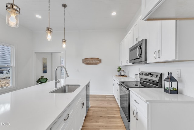 kitchen featuring sink, white cabinetry, hanging light fixtures, light wood-type flooring, and appliances with stainless steel finishes