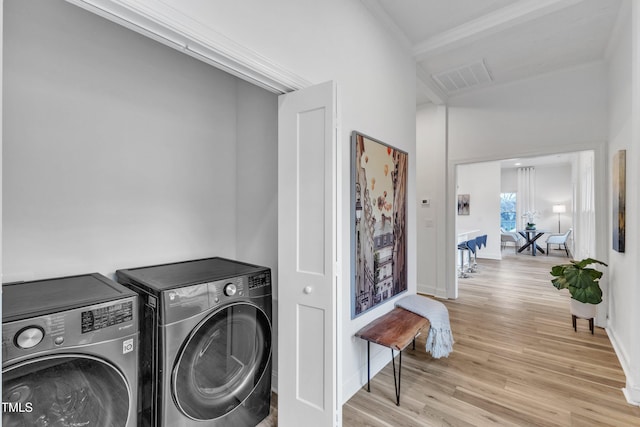 laundry room featuring crown molding, washing machine and clothes dryer, and light hardwood / wood-style floors