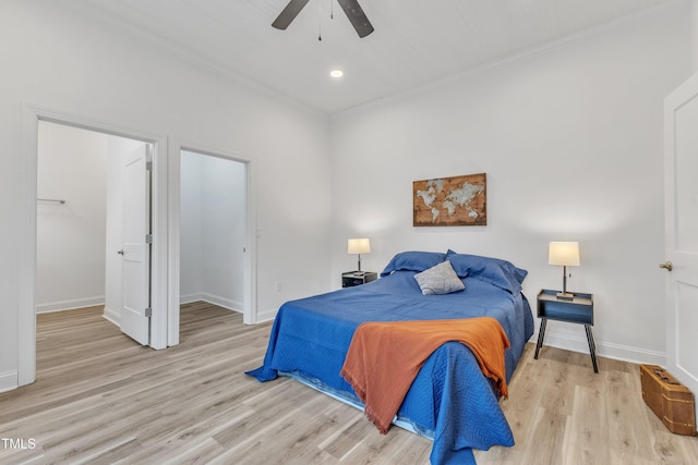 bedroom featuring ceiling fan, a spacious closet, and light hardwood / wood-style floors