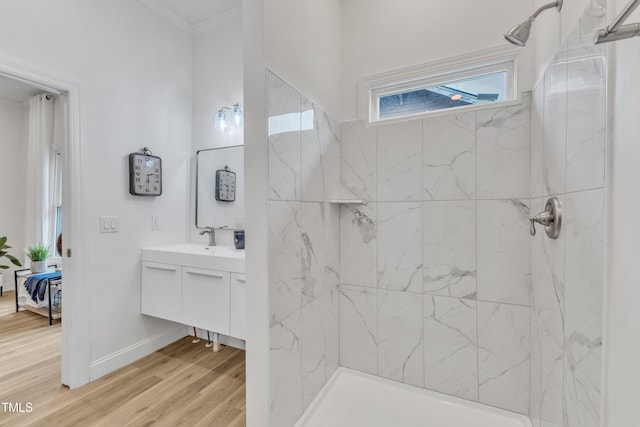 bathroom featuring vanity, crown molding, wood-type flooring, and a tile shower