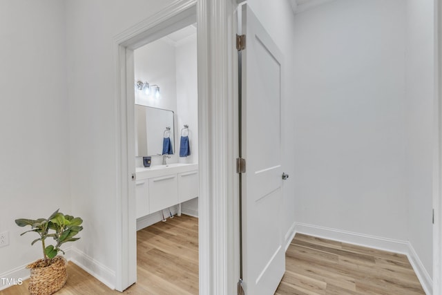 corridor with sink and light hardwood / wood-style flooring