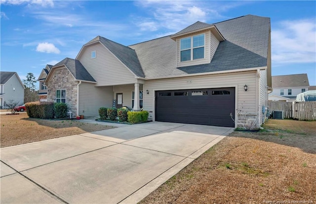 view of front facade with cooling unit, a garage, a front yard, and covered porch