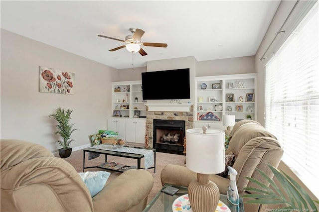 living room with a stone fireplace, carpet floors, and ceiling fan