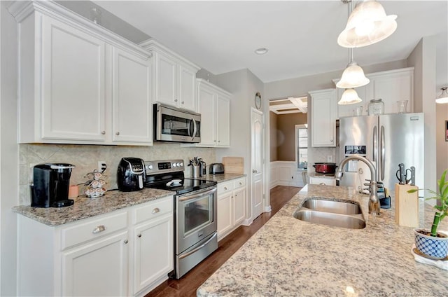 kitchen featuring appliances with stainless steel finishes, sink, pendant lighting, and white cabinets