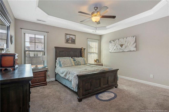 carpeted bedroom with a raised ceiling and ceiling fan